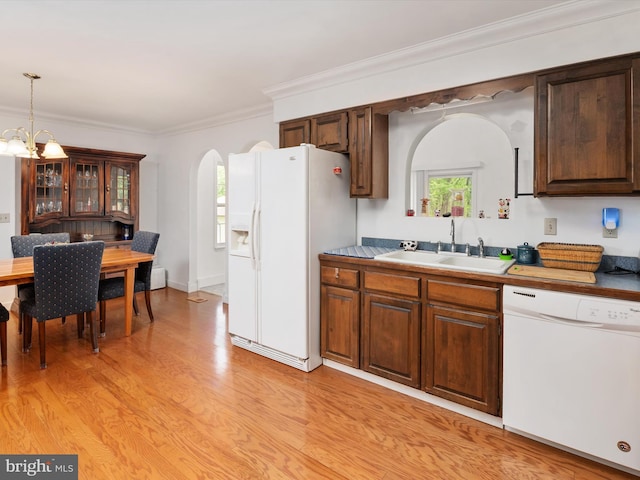 kitchen with a sink, a notable chandelier, light wood-style flooring, white appliances, and arched walkways