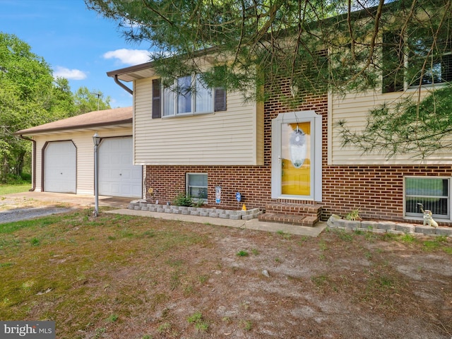 split level home with driveway, an attached garage, entry steps, and brick siding