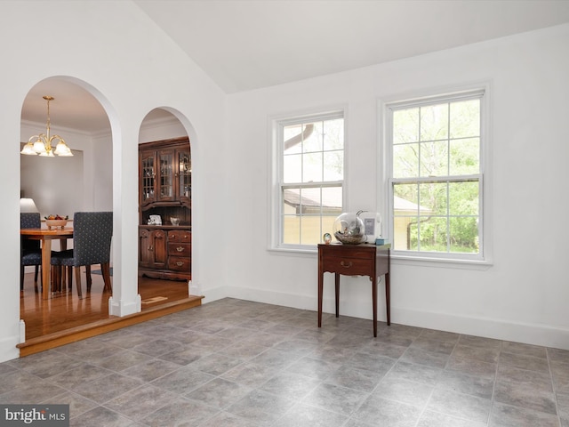 interior space featuring baseboards, stone finish floor, lofted ceiling, and plenty of natural light