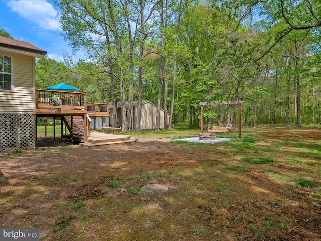 view of yard with a deck, a fire pit, stairway, an outbuilding, and a shed