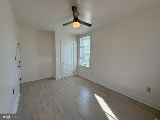 unfurnished room featuring wood finished floors, a ceiling fan, and baseboards