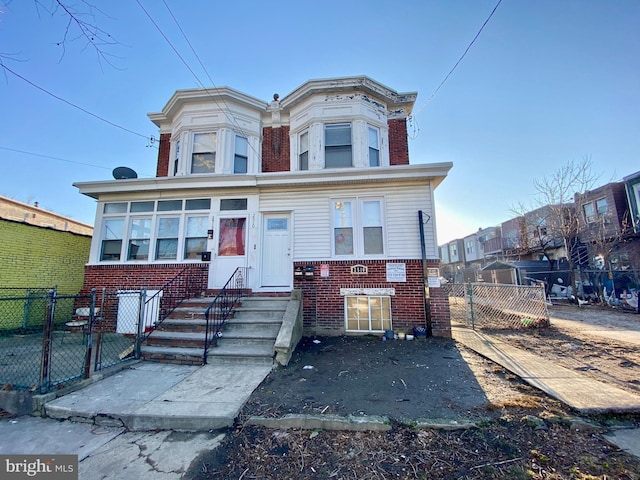 view of front facade with entry steps, fence private yard, brick siding, and a gate