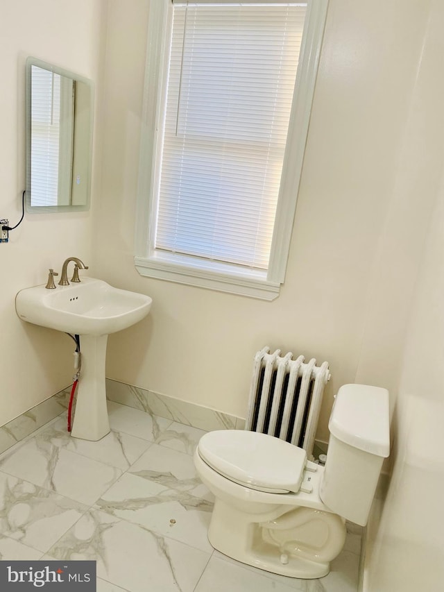 bathroom featuring a sink, toilet, baseboards, radiator heating unit, and marble finish floor