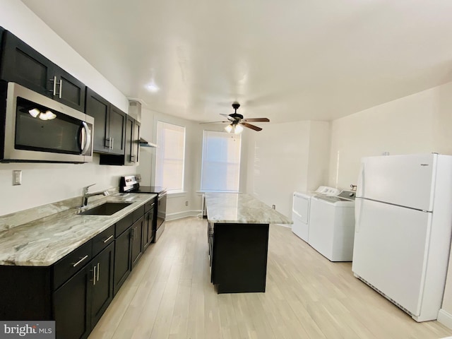kitchen with washing machine and dryer, dark cabinets, stainless steel appliances, and a sink