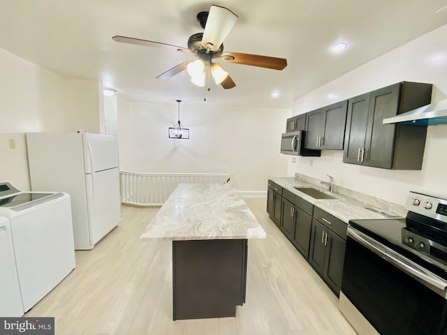 kitchen with a center island, washer and clothes dryer, a sink, ceiling fan, and appliances with stainless steel finishes