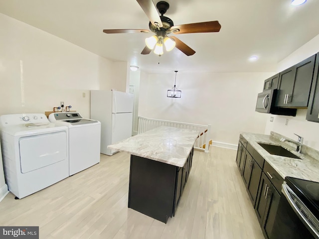 kitchen featuring freestanding refrigerator, washer and clothes dryer, dark cabinets, and a sink