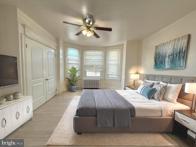 bedroom with light wood-type flooring, ceiling fan, and radiator