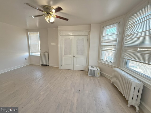 unfurnished bedroom featuring multiple windows, radiator heating unit, and light wood-style floors