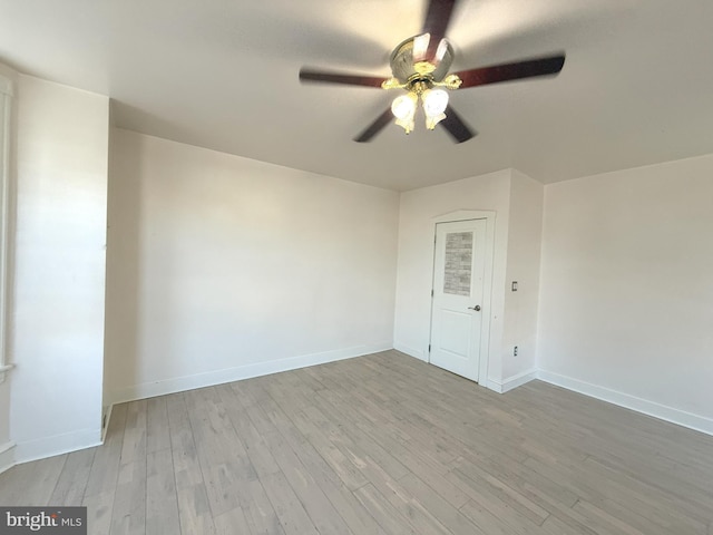 empty room with baseboards, a ceiling fan, and wood finished floors