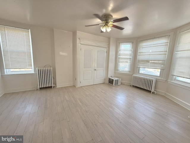 interior space with radiator heating unit, wood finished floors, and multiple windows