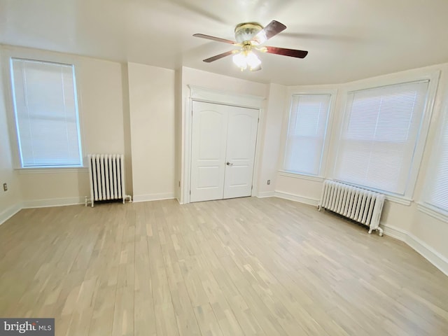 unfurnished bedroom featuring radiator, light wood-style floors, a closet, and baseboards