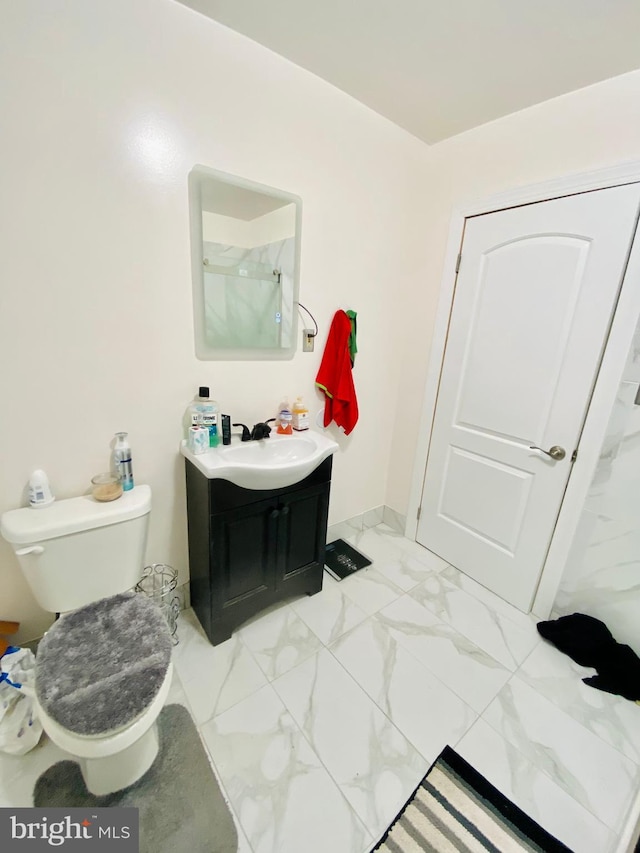 bathroom with marble finish floor, vanity, and toilet