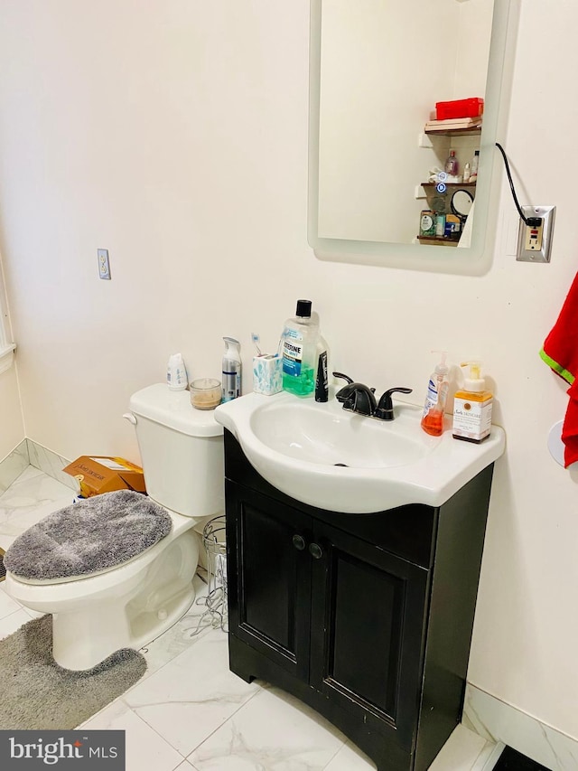 bathroom with marble finish floor, vanity, and toilet
