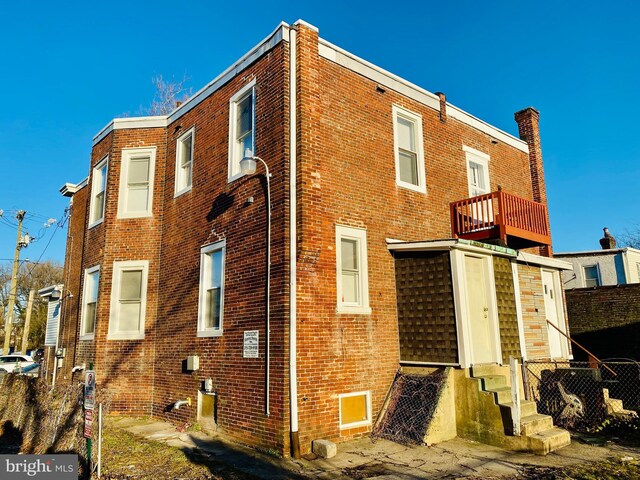 rear view of property with a chimney, brick siding, and entry steps