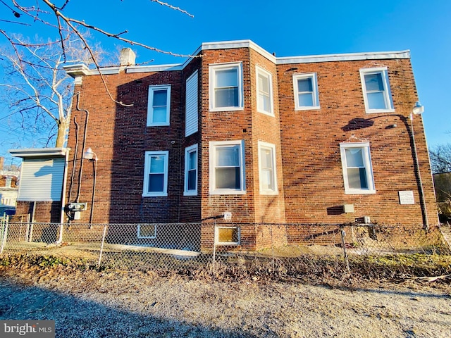 view of side of property featuring a chimney, brick siding, and a fenced front yard