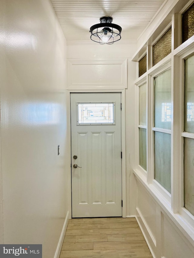 doorway to outside featuring crown molding and light wood finished floors