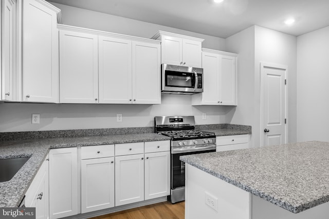 kitchen with light wood finished floors, stainless steel appliances, recessed lighting, and white cabinetry