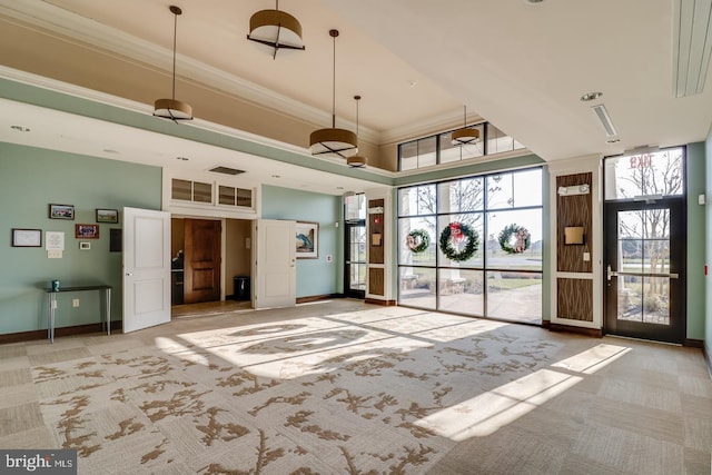 interior space featuring baseboards, ornamental molding, a high ceiling, visible vents, and light colored carpet