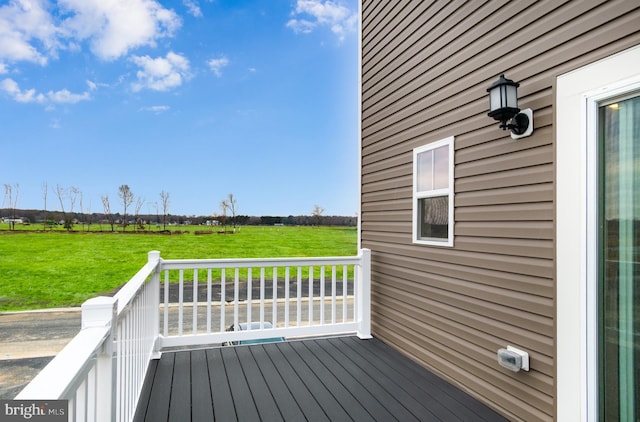 wooden terrace featuring a lawn and a rural view