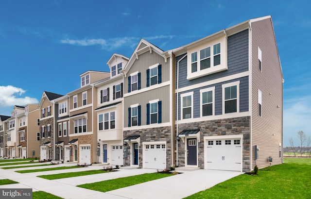multi unit property with a residential view, driveway, stone siding, an attached garage, and a front yard