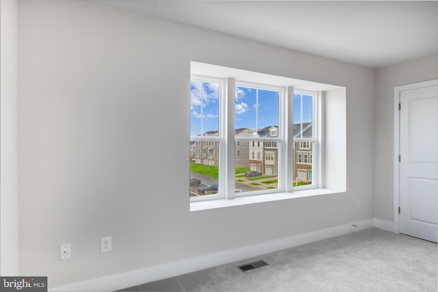 carpeted empty room with visible vents and baseboards