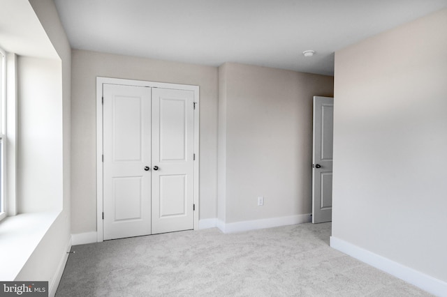 unfurnished bedroom featuring baseboards, carpet flooring, and a closet