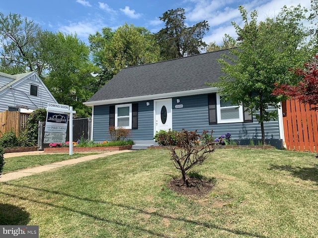 view of front of home with fence, a shingled roof, and a front yard