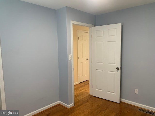 spare room featuring baseboards, wood finished floors, and visible vents