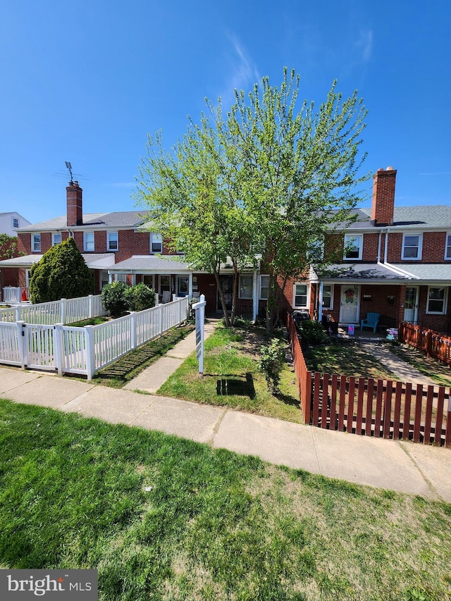 view of front of property with a front lawn, brick siding, and a fenced front yard