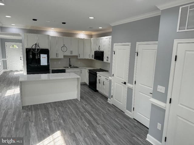 kitchen featuring black appliances, a sink, ornamental molding, dark wood-style floors, and baseboards