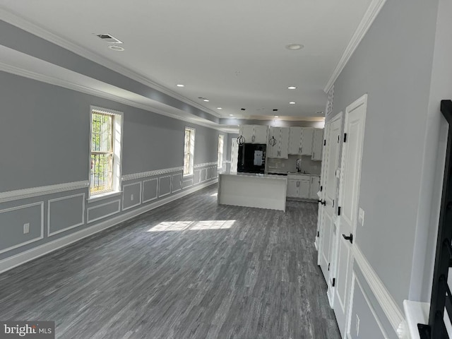 unfurnished living room featuring wainscoting, dark wood-style floors, recessed lighting, crown molding, and a decorative wall