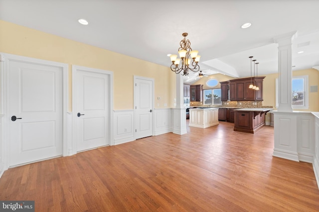 kitchen with light wood-type flooring, a notable chandelier, tasteful backsplash, and light countertops