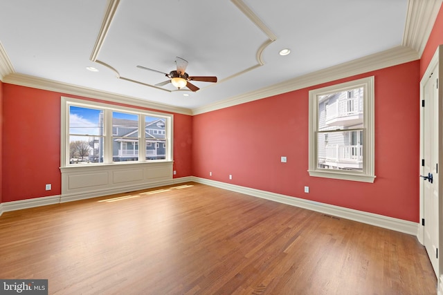 empty room featuring a healthy amount of sunlight, a ceiling fan, ornamental molding, and light wood-style floors