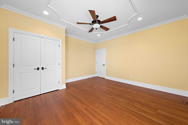 unfurnished bedroom with crown molding, a closet, baseboards, recessed lighting, and wood finished floors