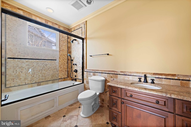 full bathroom featuring tile walls, enclosed tub / shower combo, ornamental molding, toilet, and vanity