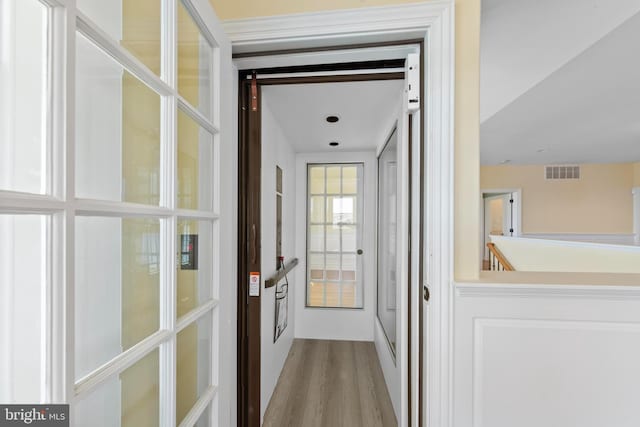 hallway with wood finished floors and visible vents