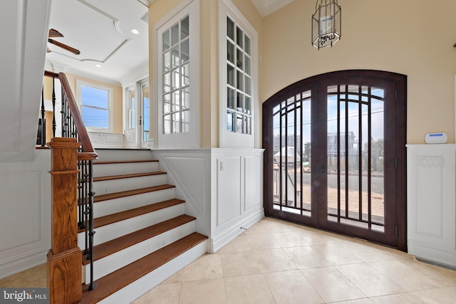 entryway with crown molding, stairway, arched walkways, light tile patterned flooring, and a ceiling fan