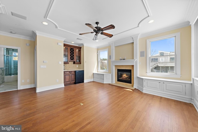 unfurnished living room featuring a high end fireplace, recessed lighting, indoor wet bar, and light wood-style flooring