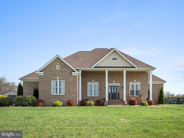 view of front facade featuring a front lawn, brick siding, fence, and a shingled roof