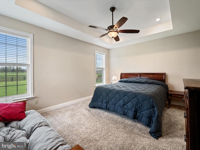 carpeted bedroom with recessed lighting, ceiling fan, baseboards, and a raised ceiling