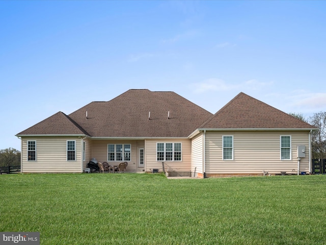 back of house featuring roof with shingles and a yard