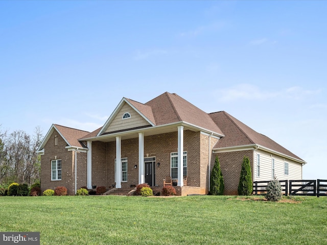 neoclassical home featuring fence, brick siding, and a front yard