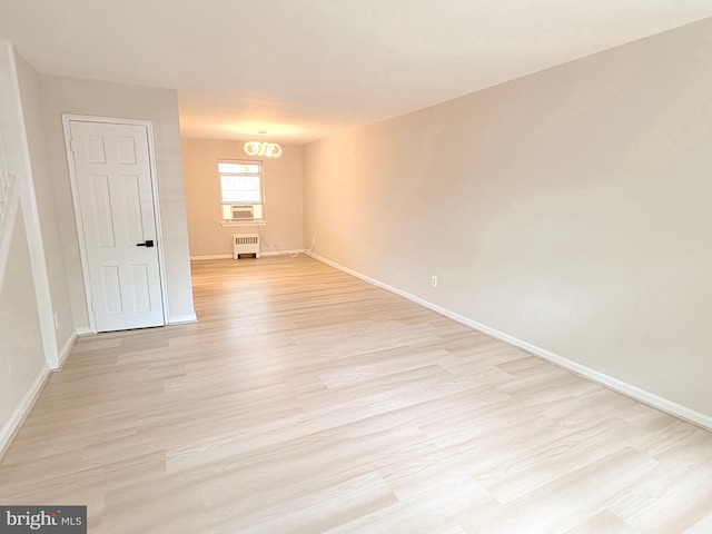 unfurnished room with radiator, baseboards, a notable chandelier, and light wood-type flooring