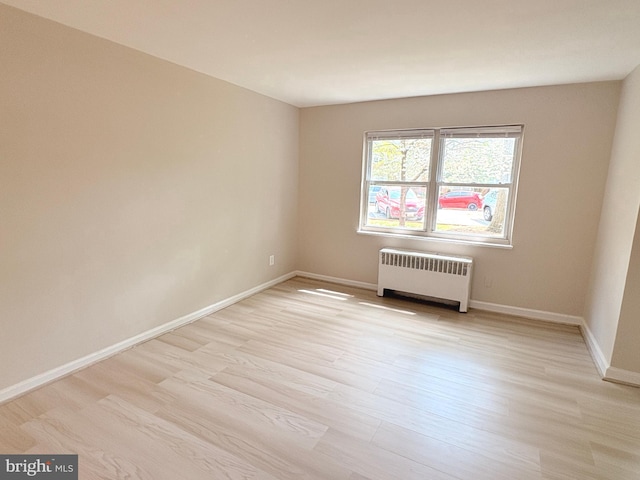 unfurnished room featuring light wood-style floors, radiator heating unit, and baseboards