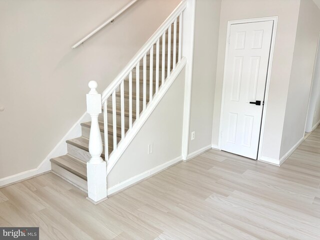 stairway with wood finished floors and baseboards