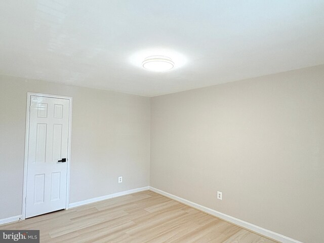 spare room featuring baseboards and light wood-style floors