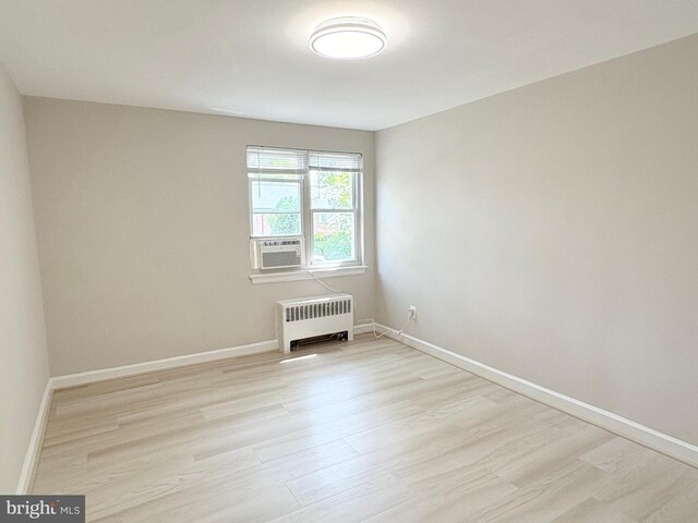 empty room featuring radiator, light wood-style flooring, and baseboards