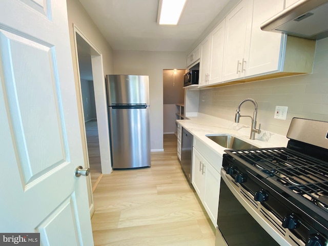 kitchen with ventilation hood, stainless steel appliances, backsplash, a sink, and white cabinetry