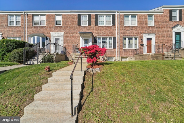 townhome / multi-family property with a front yard and brick siding