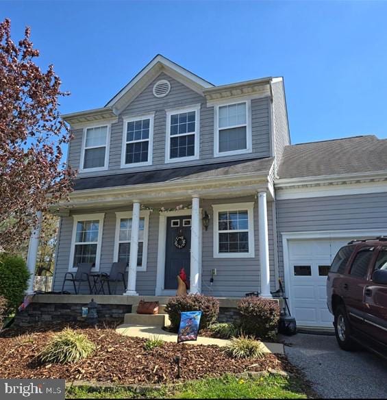 traditional-style home with a garage, aphalt driveway, and covered porch